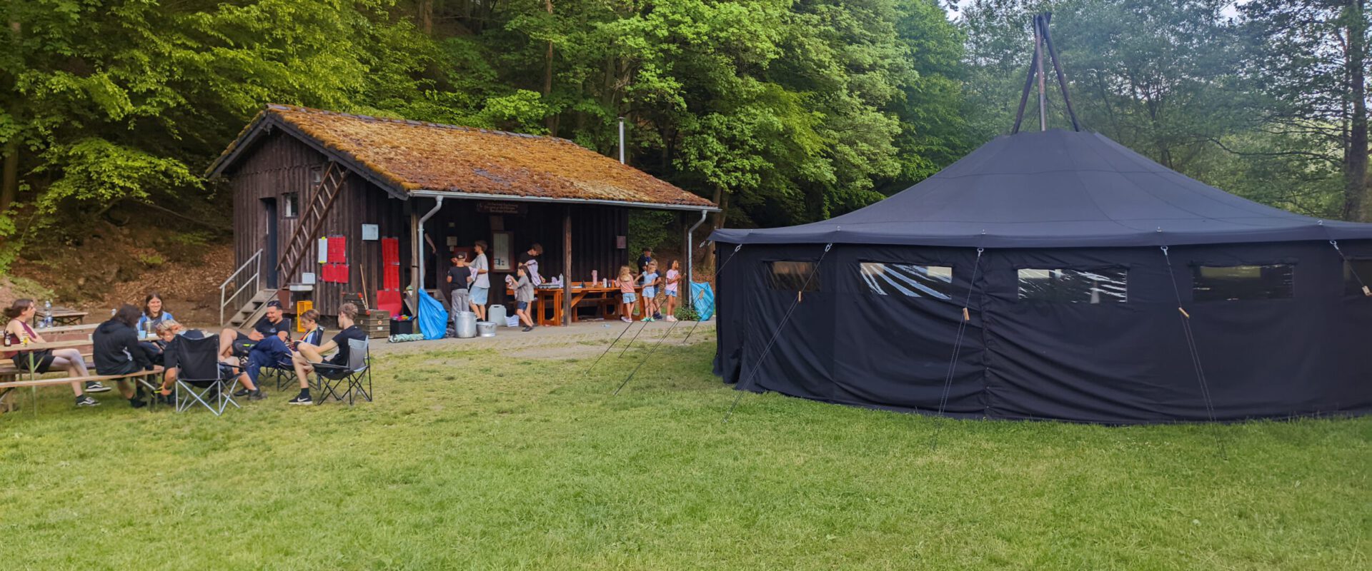 Pfingstlager 2026 1 Pfadfinder sitzen vor der Jurte und dem Waschhaus auf dem Zeltplatz